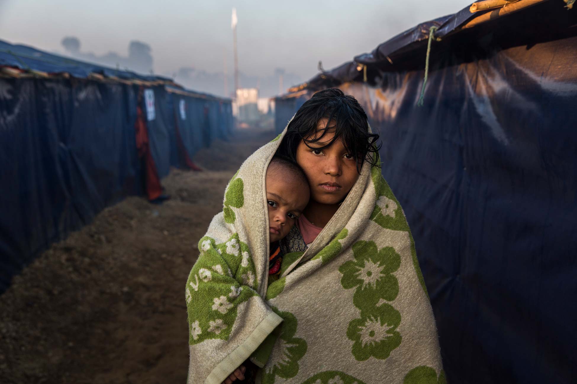 Morsheda, 12, und ihre 10 Monate alte Nichte Nisma gehen am frühen Morgen im Lager Kutupalong in Bangladesch spazieren, um sich von der Kälte in ihrer Unterkunft aufzuwärmen.