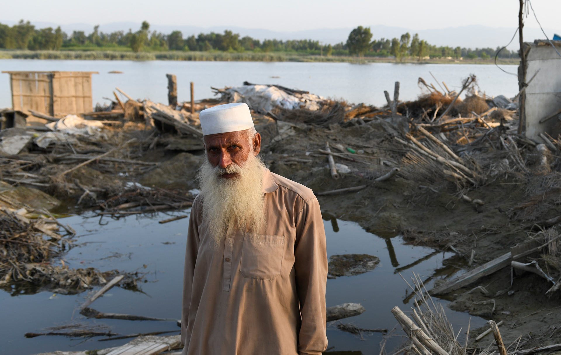 Alter Mann vor von Fluten zerstörtem Haus