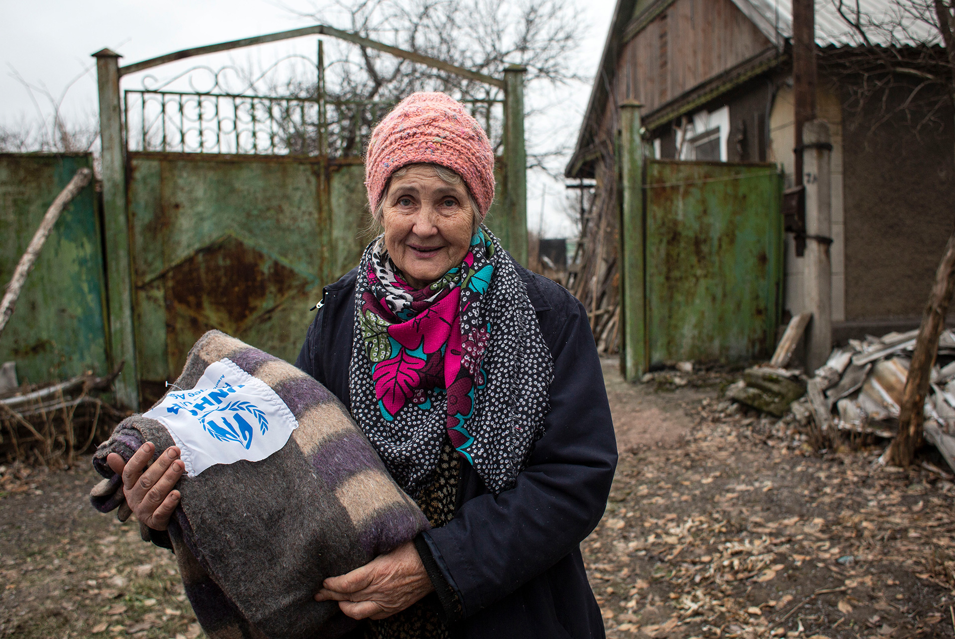 Alte Frau mit UNHCR-Decke im Arm