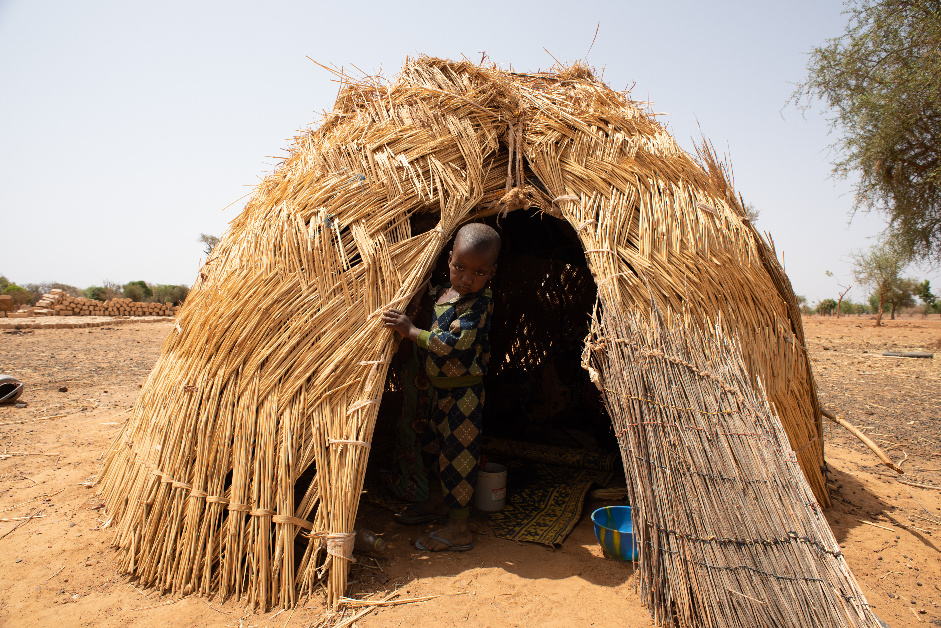 Ein Kind schaut aus einer Strohhütte raus