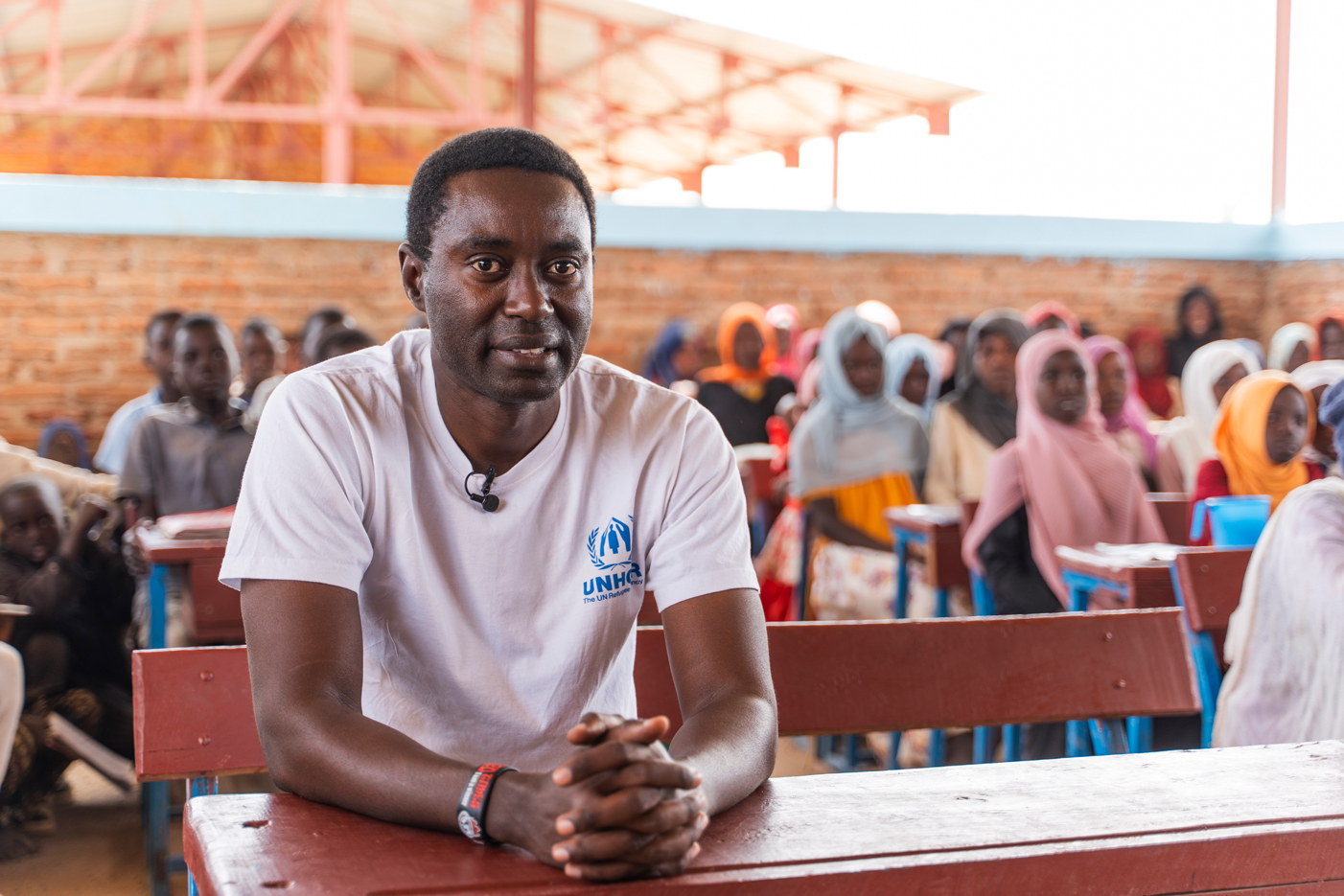 Michel-Rene Bizoza, UNHCR-Beauftragter für das Bildungswesen, ist im März 2025 im Flüchtlingslager Farchana im Osten des Tschad zu sehen, wo Schüler der Sekundarstufe einer ungewissen Zukunft entgegensehen, nachdem die Kürzungen der globalen humanitären Mittel es unmöglich gemacht haben, die Gehälter der Lehrer weiter zu zahlen. 