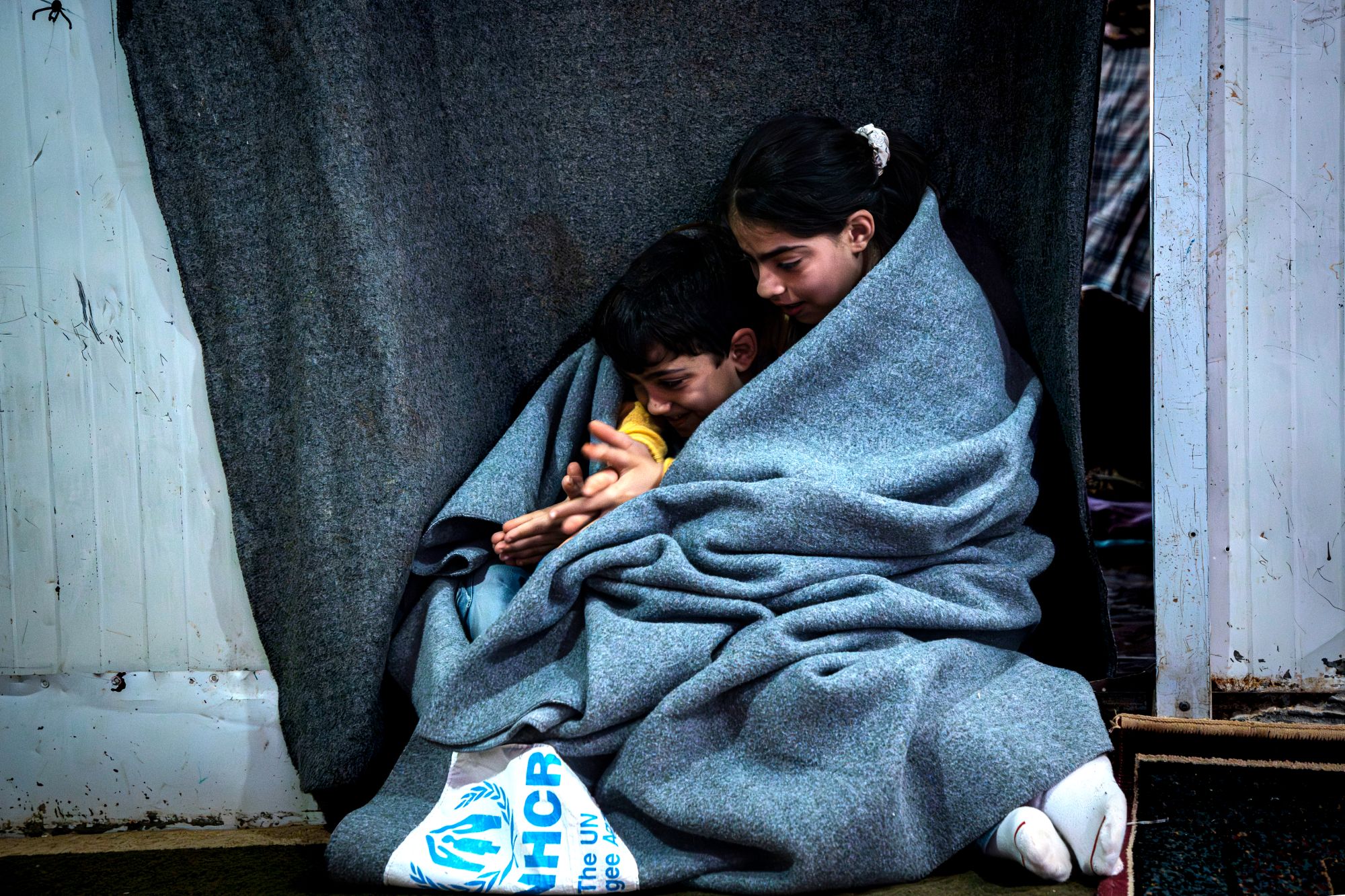 Jordanien. Die 11-jährige Sundus kuschelt mit ihrem 6-jährigen Bruder Hisham unter einer UNHCR-Decke in ihrer Unterkunft im Flüchtlingslager Zaatari. 