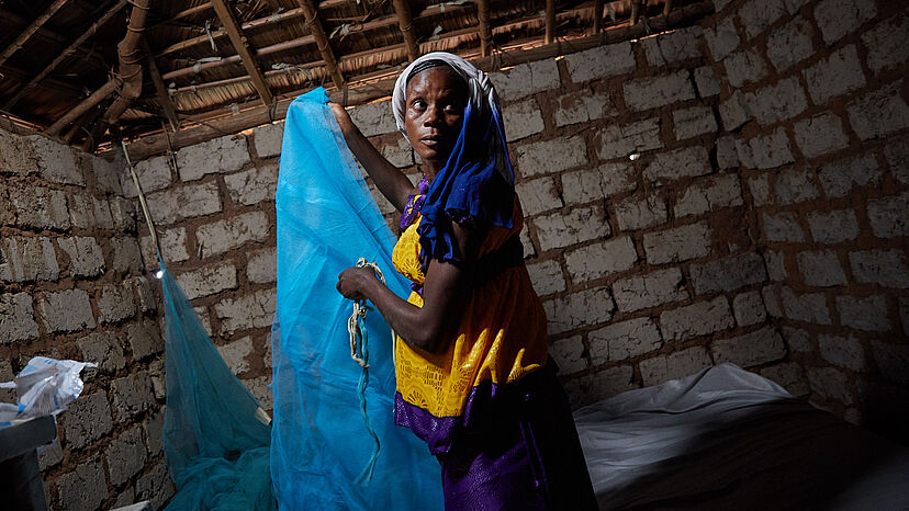 Jacquline (32) hängt ihr neues Moskitonetz auf, das sie bei einer Malaria-Aufklärungsveranstaltung des UNHCR erhalten hat. 